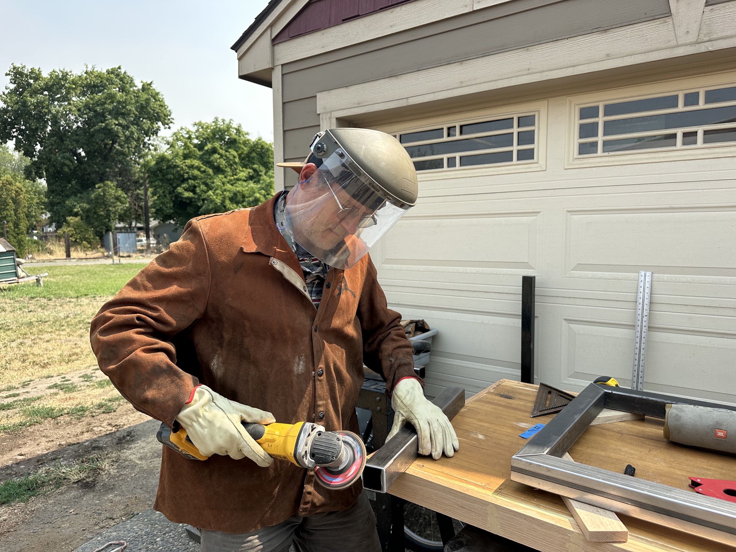 Mikhail grinding a custom steel frame on a workbench.