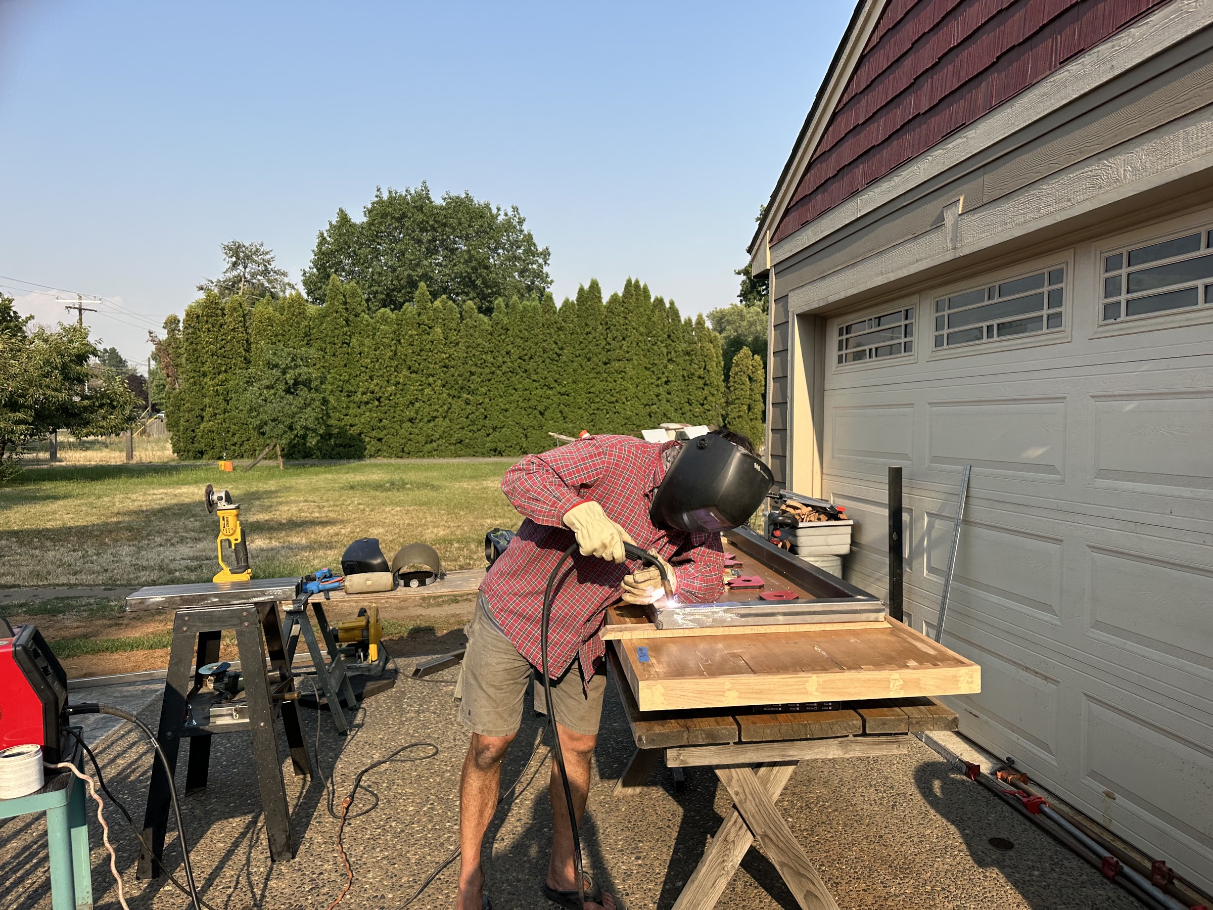 Mikhail welding a bright joint on a custom steel frame outdoors.